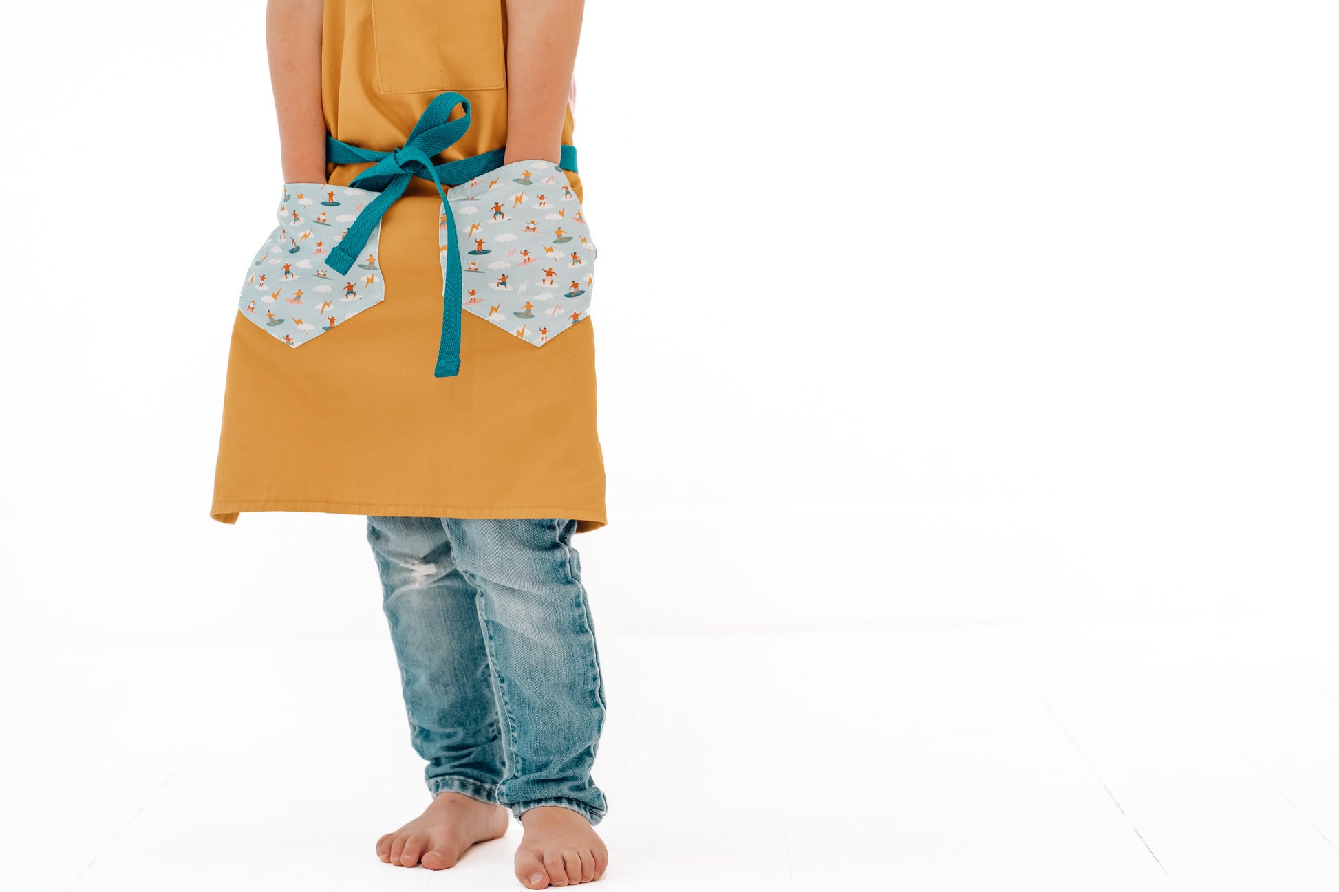 Kids craft apron Durable child apron Soft fabric apron Leather accent apron Bronze details apron Surf-themed apron Child kitchen apron Beach style apron Eco-friendly kids apron Stylish children's apron Durable apron for kids Kids cooking apron Leather strap apron Ocean design apron