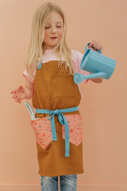 Child surf design apron Durable kids apron Soft fabric child apron Kids apron with leather accents Bronze detailed child apron Surf-themed children's apron Kids kitchen apron durable Leather strap kids apron Ocean design child apron Sturdy kids cooking apron Child apron with bronze accents High-quality kids apron Beach style children’s apron Kid-friendly surf apron